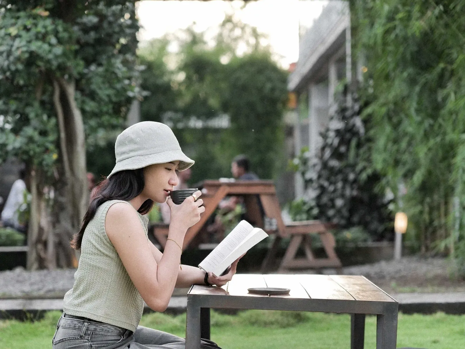 Woman reading a book while enjoying Balakosa Coffee in outdoor setting
