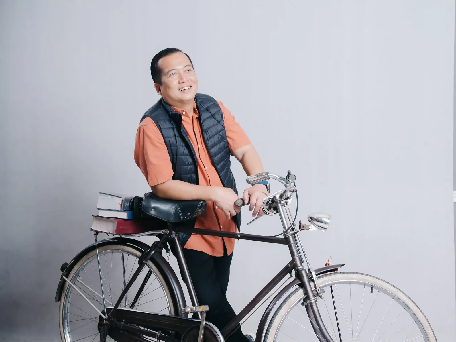 Gubernatorial candidate in orange shirt with a bicycle, representing grassroots campaign approach