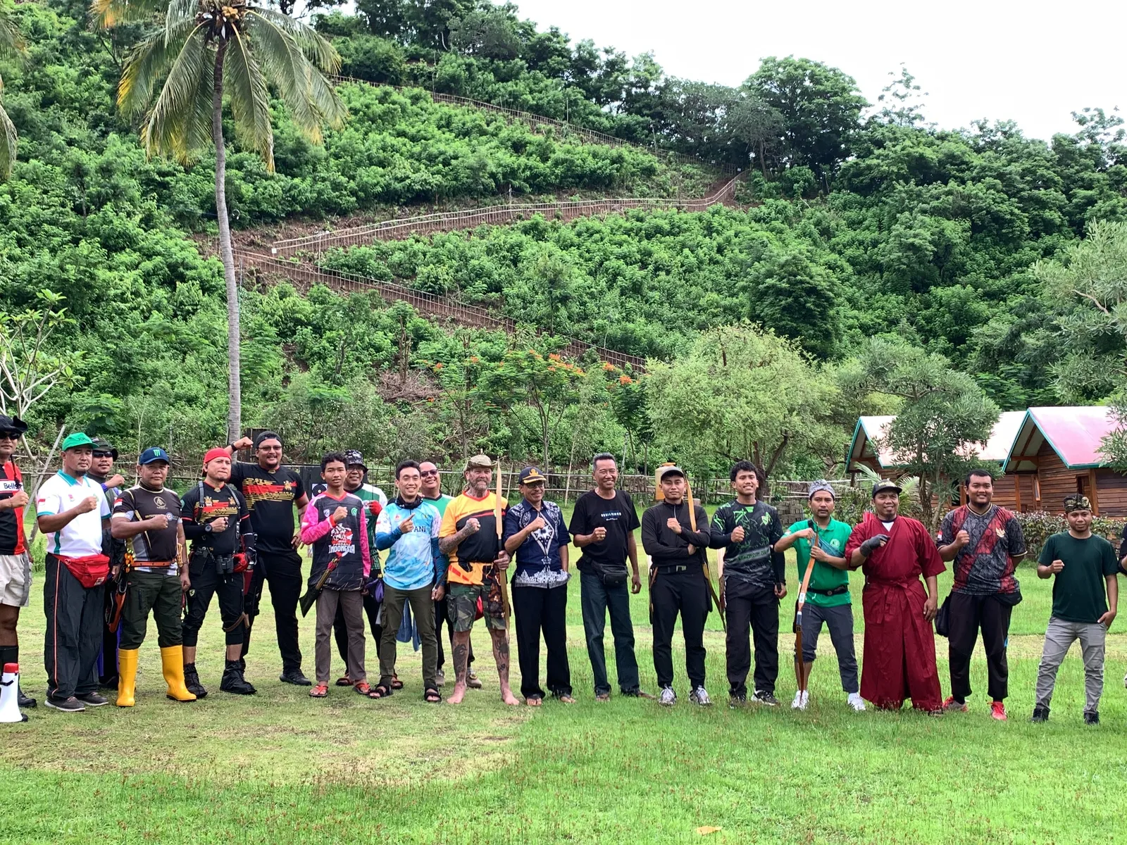Large group photo of World Field Archery participants and officials in outdoor setting with lush green hills