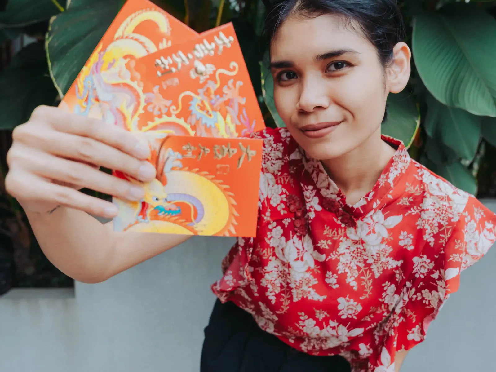 Woman in red floral top holding an orange card with Kinta Coffee branding