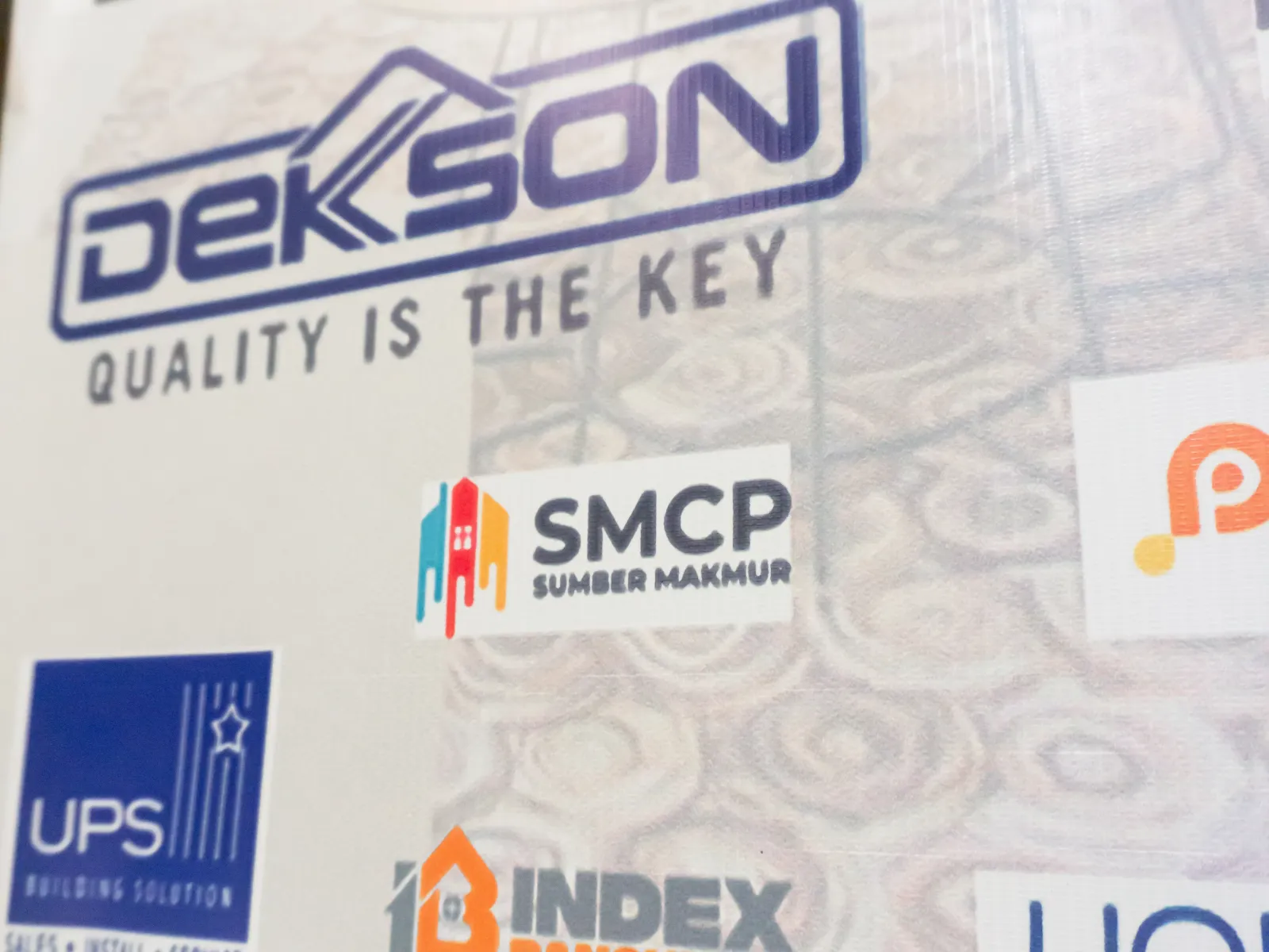 Display of various company logos including SMCP Sumber Makmur on a patterned background
